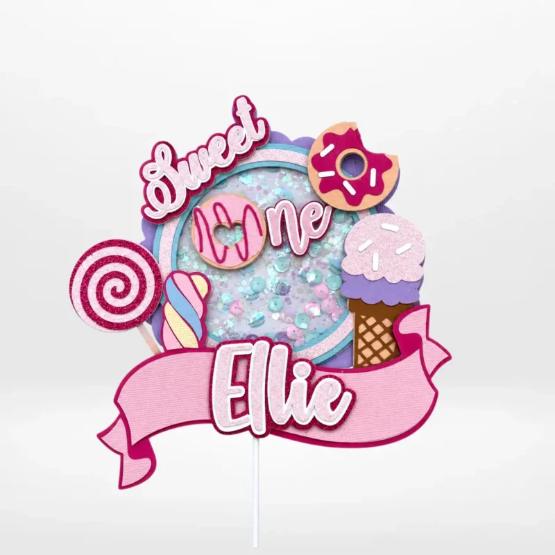 First birthday cake topper with layered 3D shaker design and sweet-themed decorations from Cake Shop Birmingham.